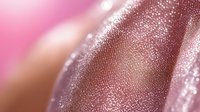 Shimmering metallic rose gold texture with glitter particles in macro shot creates luxurious abstract background with soft pink bokeh effect and selective focus.
