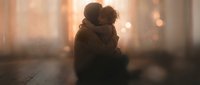 Silhouette of couple embracing in warm golden sunlight streaming through window. Romantic intimate moment with soft bokeh background for love concepts.