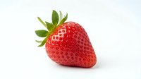 Fresh ripe strawberry with green leaves isolated on white background, ready for food and beverage design projects.