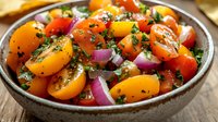 Fresh summer salad with colorful cherry tomatoes, red onions, herbs and black sesame seeds in rustic ceramic bowl, close up view of healthy appetizer.