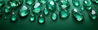 Sparkling emerald water drops scattered on dark green surface creating luxurious border composition with reflections and transparency effects.