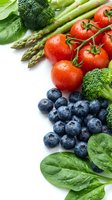 Fresh organic vegetables and berries with water droplets on white background for healthy eating and nutrition concepts.