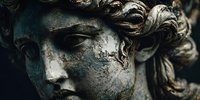 Ancient weathered stone sculpture face with curly hair showing signs of age and erosion. Classical art statue detail for historical and cultural projects.