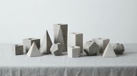 Minimalist concrete geometric shapes arranged on linen surface showcasing modern architectural forms and abstract sculptural elements for contemporary design.