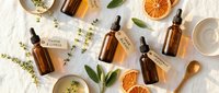 Natural organic skincare products with essential oil bottles, dried orange slices and herbs on white marble background for spa wellness routine.