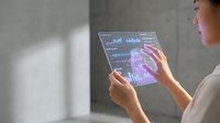 Woman using futuristic transparent tablet with holographic data visualization and charts for business analytics and financial technology applications.