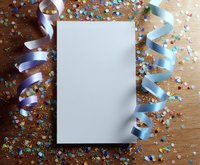 Blank white paper mockup with festive blue and purple ribbons and colorful confetti scattered on wooden background. Party invitation or celebration design template.