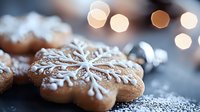 Festive gingerbread cookie decorated with white royal icing snowflake pattern on dark background with soft bokeh lights and powdered sugar dusting.