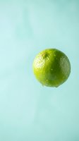 Fresh green lime with water droplets isolated on soft turquoise background, suitable for food and beverage design projects.