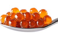Red caviar spheres on silver spoon against white background, fresh salmon roe close up with translucent texture and natural shine for gourmet food design.