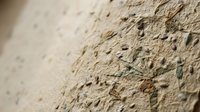 Rough textured concrete wall surface with natural stone aggregate and pebbles embedded in cement material for construction and architectural backgrounds.