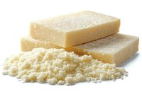 Fresh grated parmesan cheese blocks and powder on white background, dairy product close-up macro photography for culinary and food industry use.