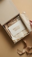 Elegant open gift box with special offer card nestled in tissue paper, beige tones, luxury unboxing concept for retail and marketing.