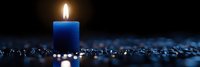 Glowing blue candle flame against dark background with scattered sparkles creates peaceful ambiance. Panoramic composition for meditation and spiritual concepts.