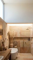 Modern minimalist bathroom interior with warm wood tones, freestanding bathtub, walk-in shower, and natural decor elements for spa-like ambiance.