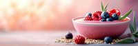 Pink smoothie bowl topped with fresh berries, granola and mint leaves on wooden surface with soft bokeh background for healthy breakfast concepts.