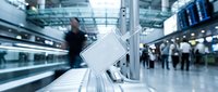 Modern airport terminal with charging station and blurred travelers in background, showcasing contemporary travel infrastructure and passenger services.