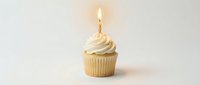Vanilla cupcake with cream frosting and lit golden candle on white background, suitable for birthday celebrations, bakery marketing, and festive occasions.