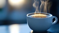 Steaming hot coffee in white ceramic cup against blurred blue background, with rising vapor and golden crema on top creating cozy morning atmosphere.