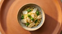 Fresh pasta with herbs and parmesan cheese served in rustic ceramic bowl on wooden table for Italian cuisine and homemade cooking concepts.