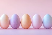 Pastel colored Easter eggs in row on pink background. Natural speckled eggshells in soft peach, lavender, coral, rose and mint shades create minimal spring composition.