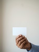 Mature male hand holding blank white card against neutral background, suitable for business messaging, corporate communication, and professional advertising campaigns.