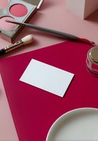 Blank business card mockup on vibrant pink background with makeup brushes, blush palette and cosmetic jar for beauty branding presentation.
