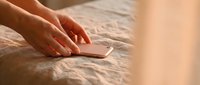 Woman hands placing smartphone on bed in warm morning light creating intimate bedroom atmosphere for technology and lifestyle concepts.
