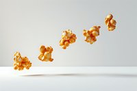 Floating popcorn kernels in diagonal line against white background, levitating caramel popcorn pieces captured in motion with soft shadows.