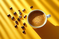 Fresh coffee cup with crema foam and scattered roasted beans on vibrant yellow background with diagonal shadow lines creating modern minimalist composition.