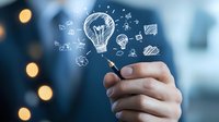 Creative business concept with hand drawing glowing light bulb and innovation icons in white chalk style on blurred background with bokeh lights.