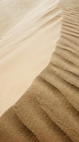 Aerial view of desert sand dunes with rippled patterns and smooth slopes, showcasing natural textures and warm earth tones for landscape and nature backgrounds.