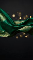 Luxurious emerald green silk fabric with golden ornate patterns flowing elegantly against dark background with warm bokeh lights for premium design projects.