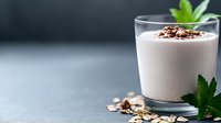 Creamy yogurt parfait with chocolate granola and fresh mint leaves in glass on gray background, healthy breakfast or dessert concept.