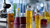 Laboratory glassware with colorful liquid samples in glass bottles and microscope in background, scientific research concept in modern lab setting.