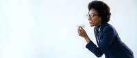 Professional African American businesswoman in navy suit holding coffee cup during office break with copy space for corporate marketing materials.