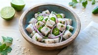 Fresh ceviche with white fish, red onions, cilantro and lime in rustic wooden bowl on light background for culinary and restaurant menu design.