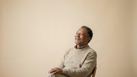 Middle-aged man with dark hair and beard, wearing a light beige sweater, seated against neutral background. Suitable for corporate, lifestyle, and editorial use.