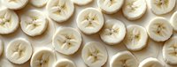 Fresh sliced bananas arranged in neat rows on white background, showing cross sections with natural star pattern in center, food photography panoramic view.