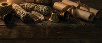 Vintage nautical items including rope, compass, rolled maps and brass telescope arranged on weathered wooden surface for maritime adventure themes.