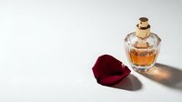 Elegant glass perfume bottle with golden cap and deep red rose petal on white background. Luxury fragrance and beauty concept for cosmetic design.