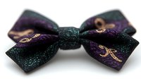 Elegant hair bow accessory in dark purple and teal with ornate golden pattern detail, photographed on white background, suitable for fashion and beauty content.