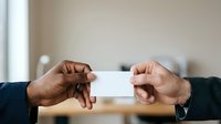 Two men exchanging blank white business card in office setting, professional networking and corporate communication concept for business meetings and partnerships.