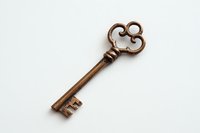 Vintage copper skeleton key with ornate bow design on white background, isolated antique decorative element for crafting and design projects.