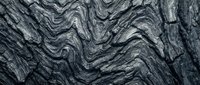 Dark gray marble stone texture with dramatic wavy veining patterns and natural rock formations for luxury interior design and architectural backgrounds.