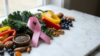 Pink ribbon with healthy foods including kale, berries, nuts and vegetables on marble surface for breast cancer awareness and nutrition education.