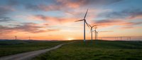 Wind turbines generating clean renewable energy on green hills during golden sunset with dramatic colorful sky and rural road for sustainable power concepts.