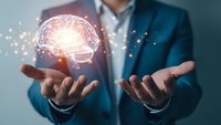 Professional businessman in suit holding glowing brain hologram with network connections representing artificial intelligence and innovation concepts.