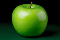 Fresh green apple with glossy skin and natural stem on dark background, symbolizing healthy eating, organic food, and nutrition concepts.