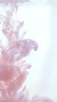 Pink and purple ink swirling in water creating abstract fluid patterns on white background for creative design projects.